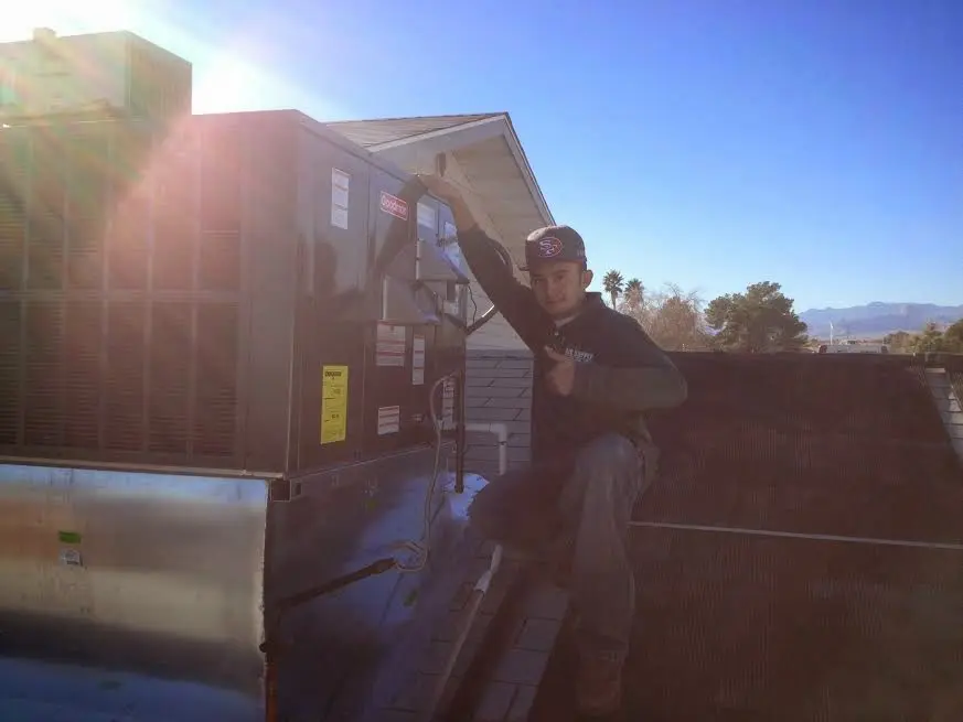 HVAC technician performing Air Duct Cleaning on a rooftop unit in Malverne